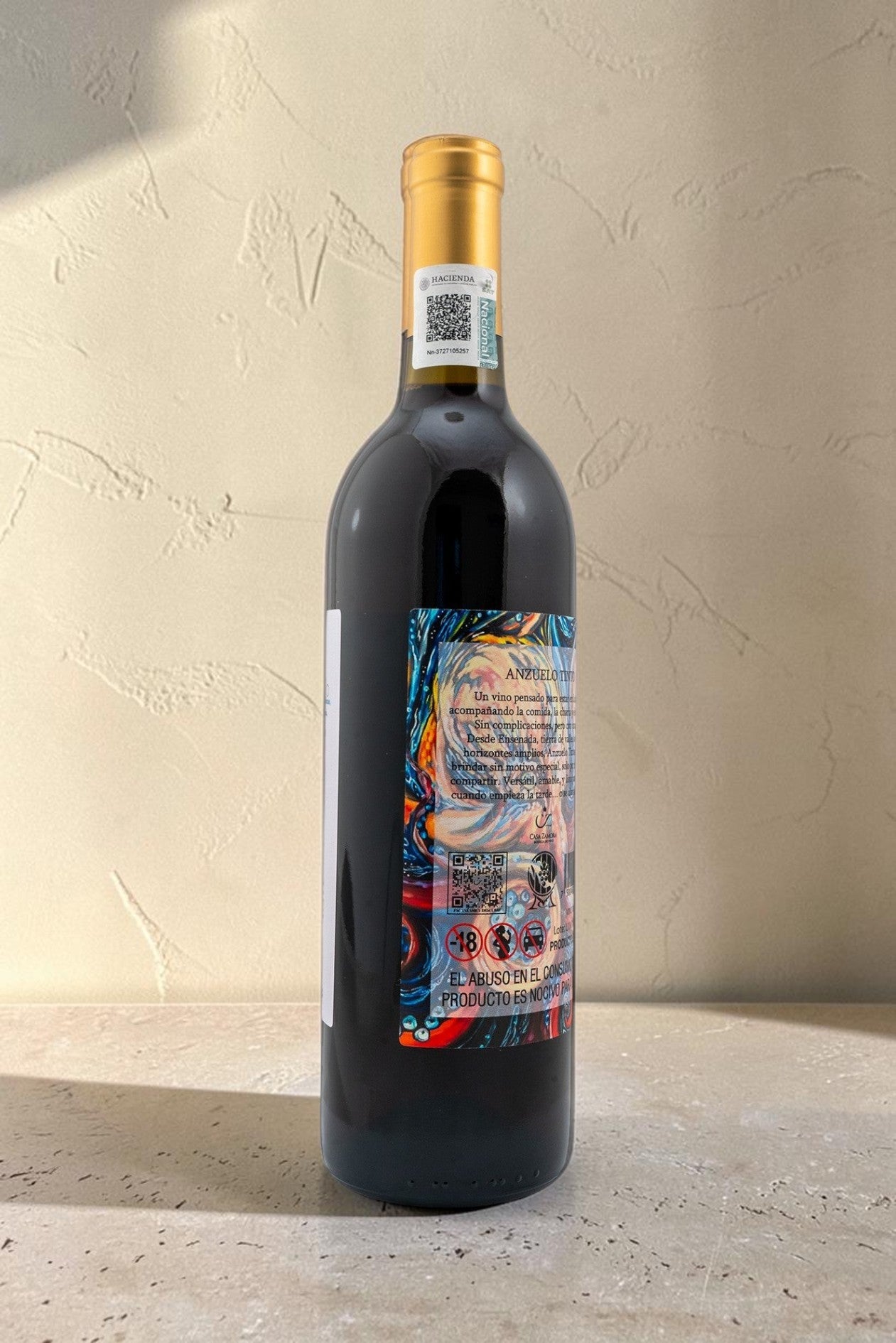 Botella de vino tinto Wellnex Anzuelo con etiqueta colorida y cápsula dorada sobre fondo neutro