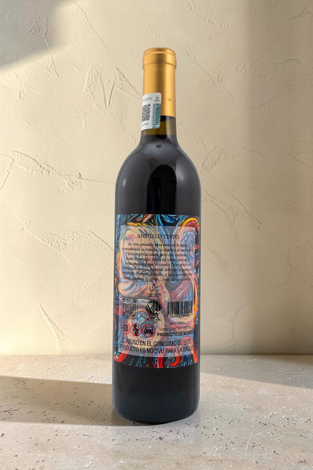 Botella de vino tinto Wellnex Anzuelo con etiqueta colorida y abstracta sobre fondo de pared texturizada