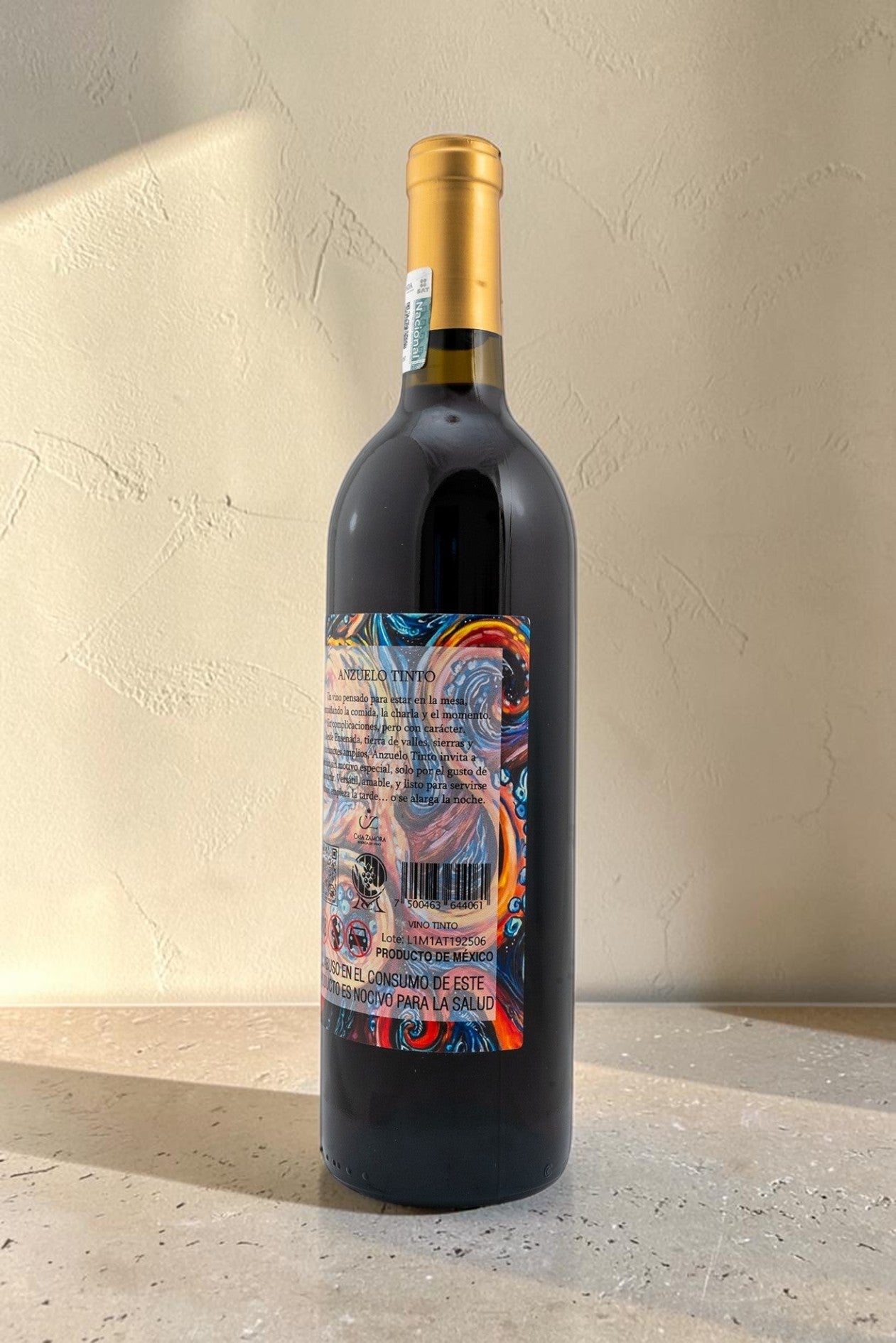 Botella de vino tinto Wellnex Anzuelo con etiqueta colorida y cápsula dorada sobre superficie clara