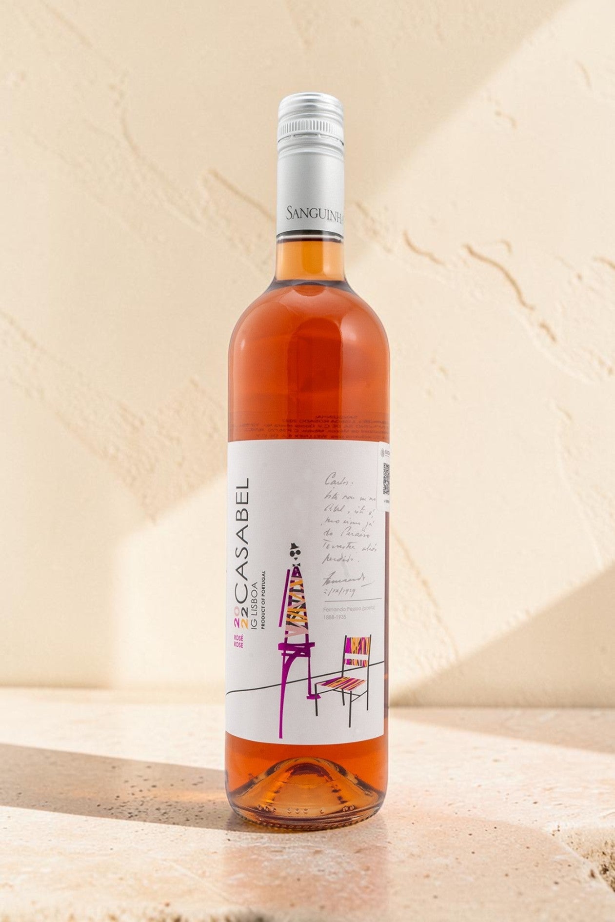 Botella de vino rosado Wellnex Casabel con etiqueta artística sobre superficie de piedra clara