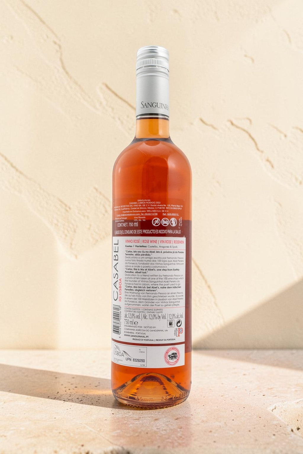 Botella de vino rosado Wellnex Casabel con etiqueta informativa sobre fondo de piedra clara