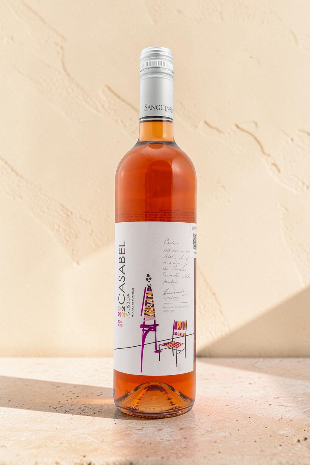 Botella de vino rosado Wellnex Casabel con etiqueta artística, tonos salmón y tapón de rosca sobre fondo texturizado