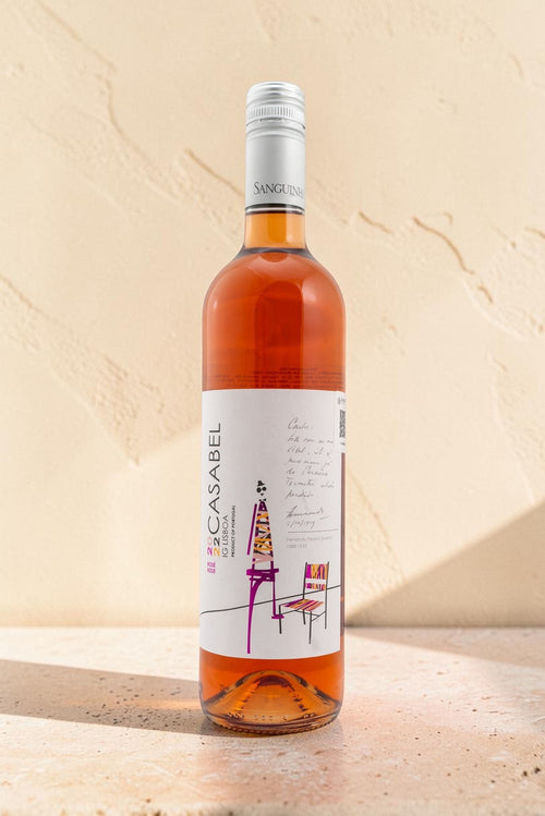 Botella de vino rosado Wellnex Casabel con etiqueta artística, tonos salmón y tapón de rosca sobre fondo texturizado