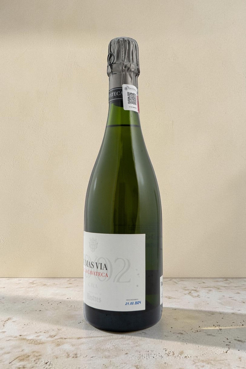 Botella de cava Mestres Cavateca MAS VIA 2002 de Wellnex sobre una superficie clara con iluminación natural