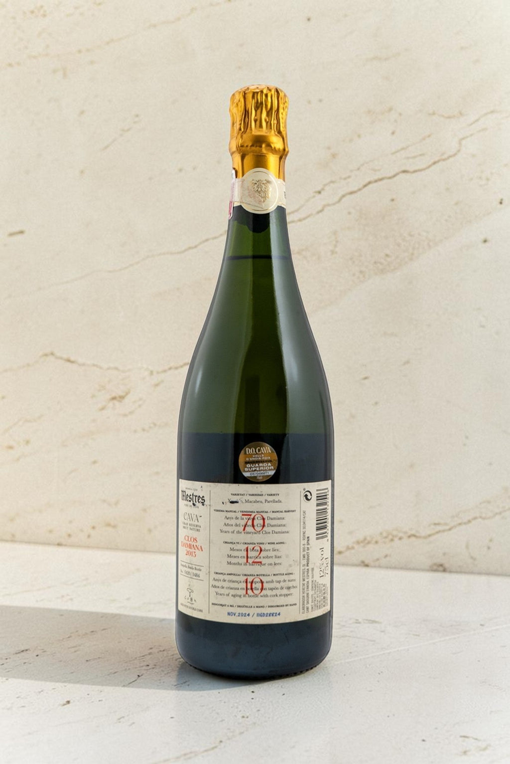 Botella de cava Wellnex Mestres Clos Damiana con etiqueta detallada sobre fondo de piedra clara