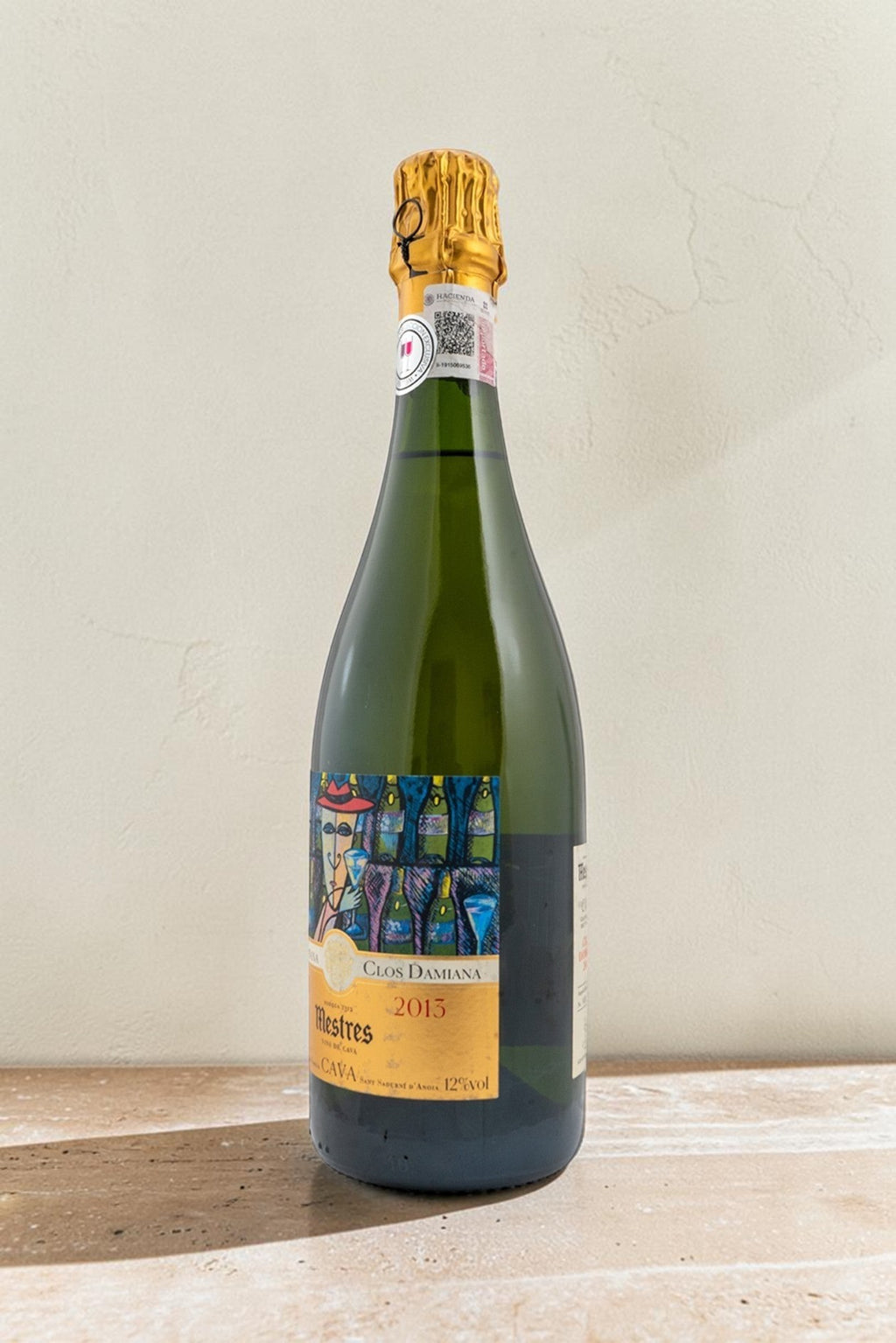 Botella de cava Wellnex Mestres Clos Damiana 2015 con etiqueta artística colorida sobre fondo neutro