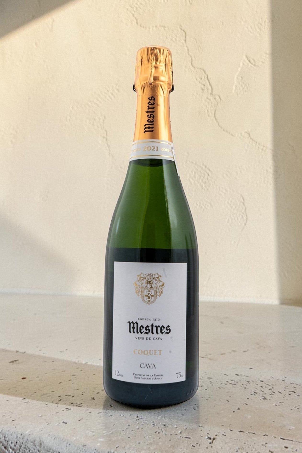 Botella de cava Wellnex Mestres Coquet con etiqueta elegante, cápsula dorada y vidrio verde sobre fondo neutro