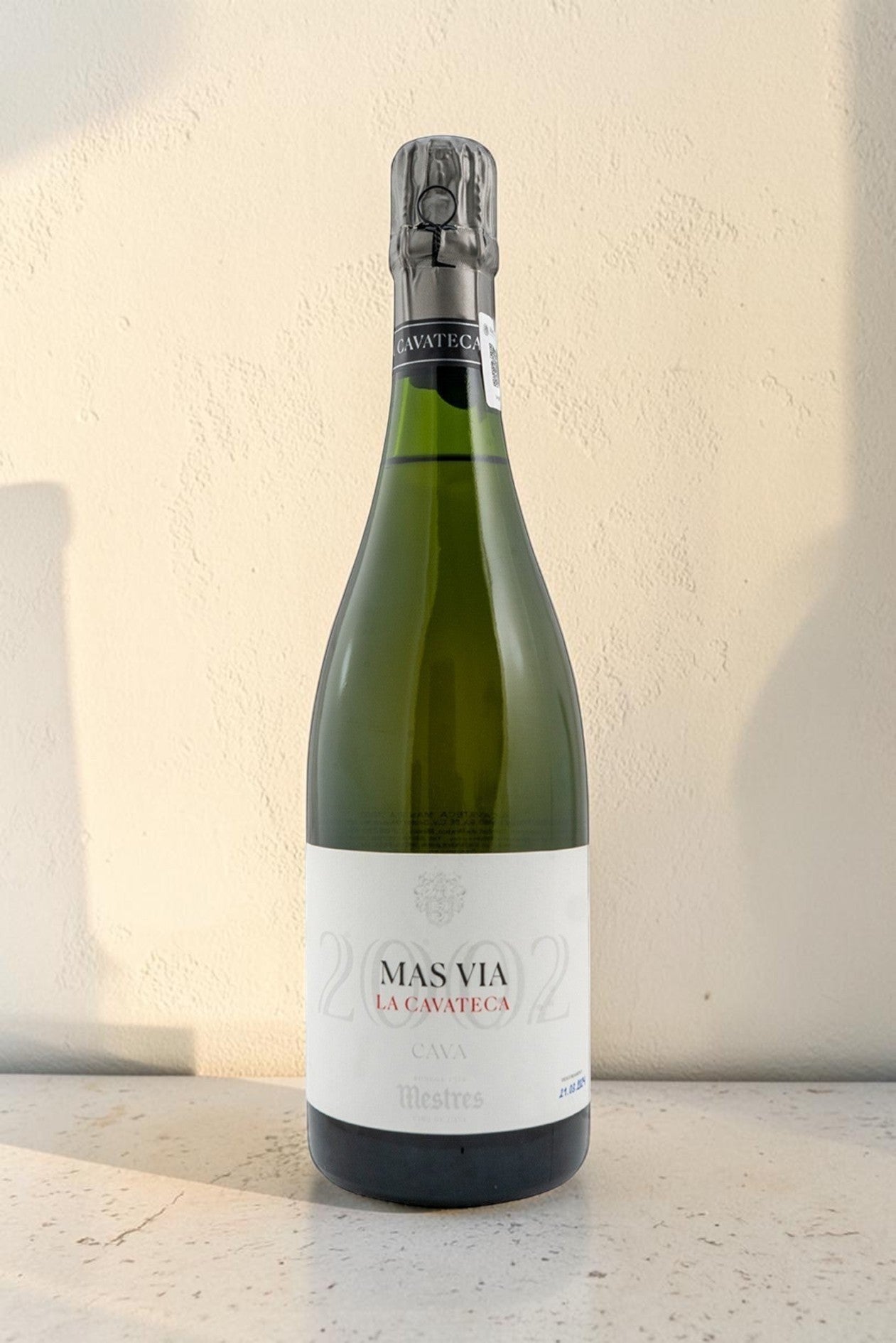 Botella de cava Wellnex Mestres Cavateca MAS VIA 2002 con etiqueta elegante sobre fondo neutro