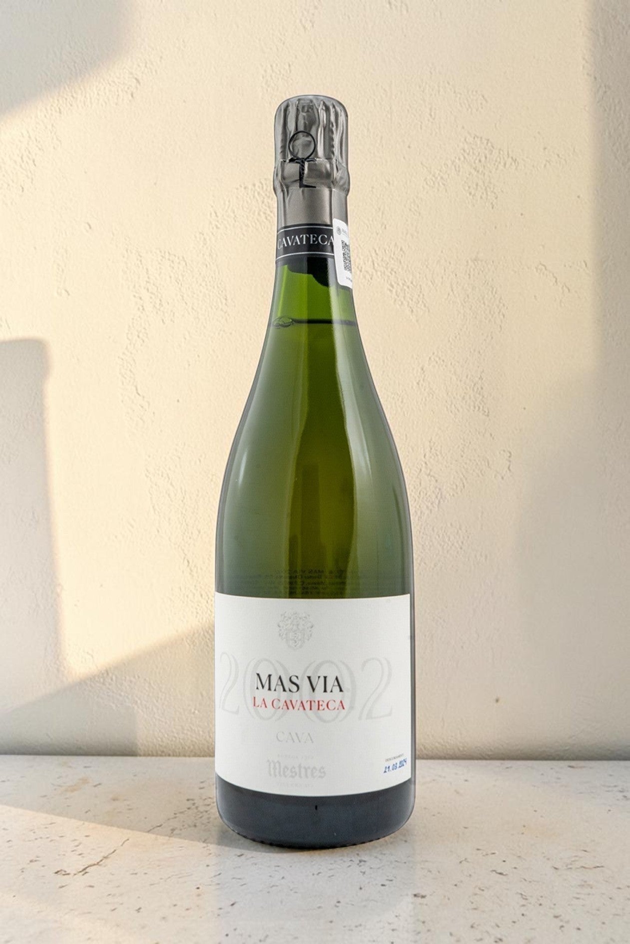 Botella de cava Mestres Cavateca MAS VIA 2002 de Wellnex sobre superficie clara con iluminación natural