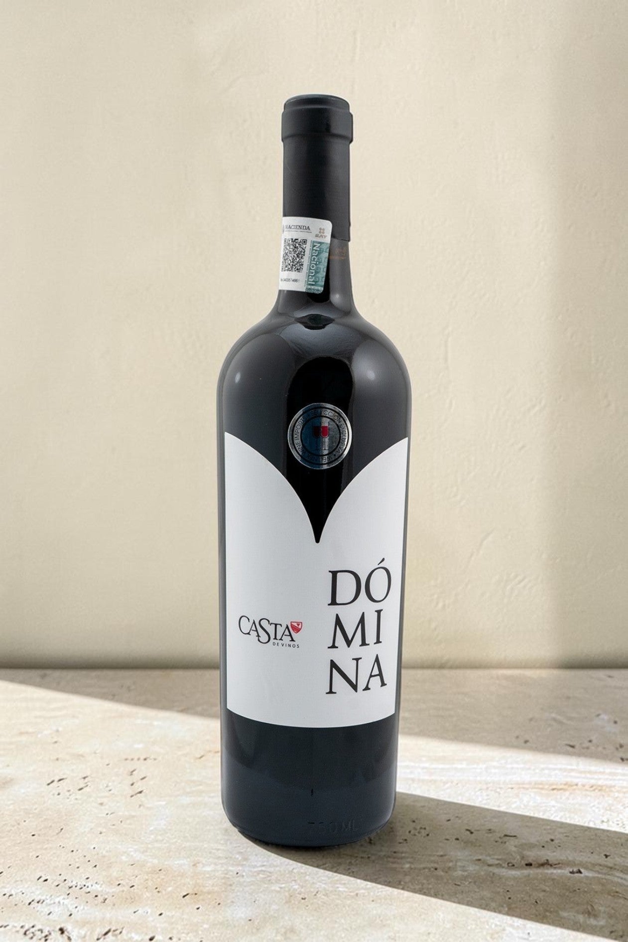 Botella de vino tinto Domina Magnum de Wellnex con etiqueta blanca minimalista sobre fondo neutro