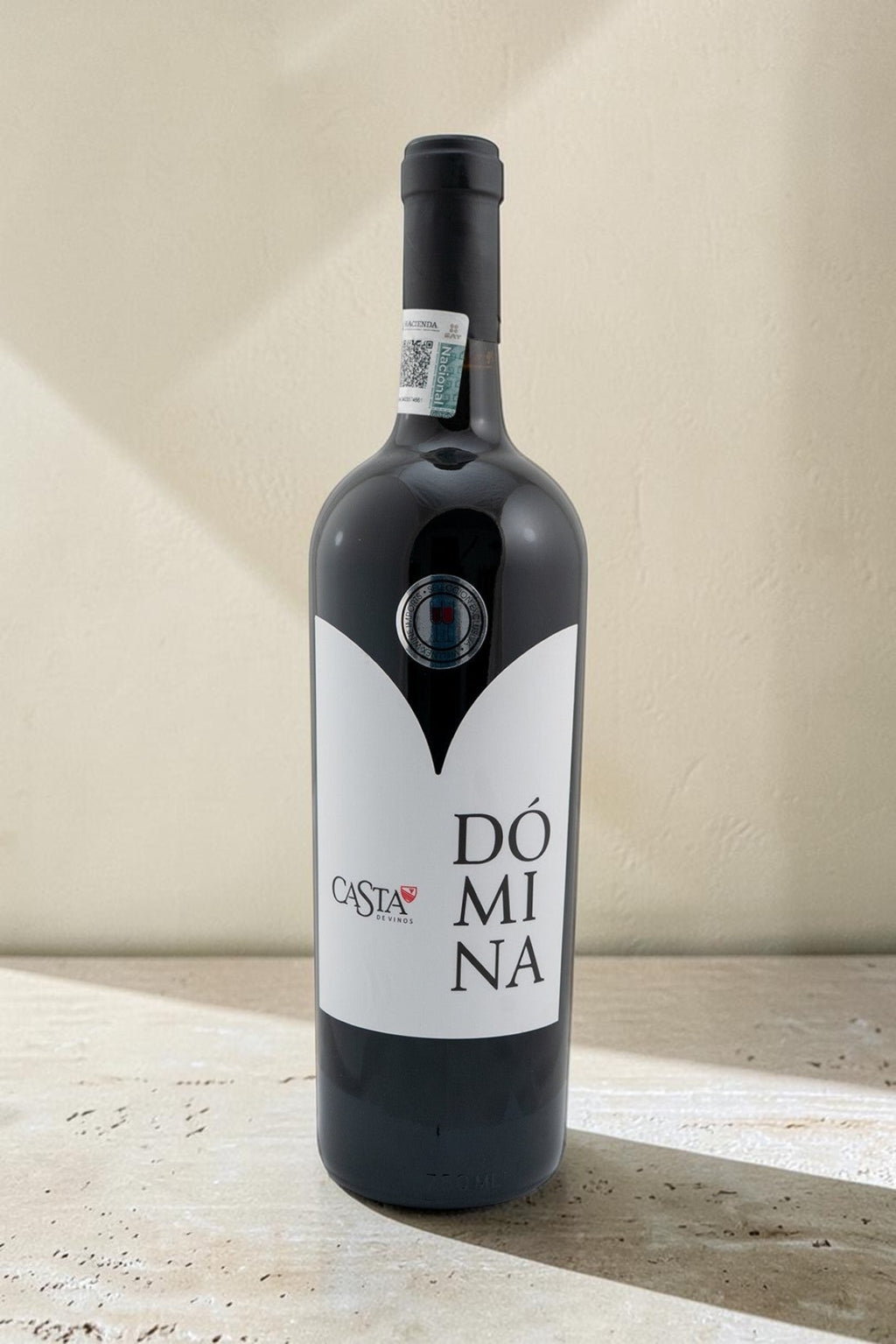 Botella de vino tinto Domina Magnum de Wellnex con etiqueta blanca sobre fondo neutro