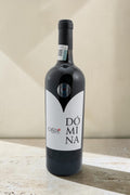 Botella de vino tinto Domina Magnum de Wellnex con etiqueta blanca sobre fondo neutro