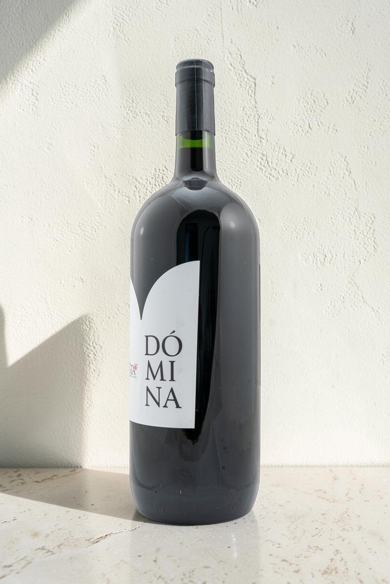 Botella de vino tinto Domina de Wellnex con etiqueta minimalista sobre fondo claro
