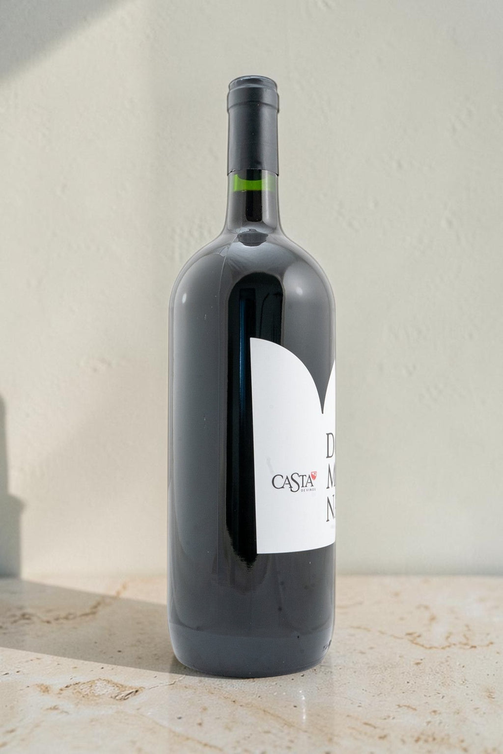 Botella de vino tinto Domina de Wellnex con etiqueta blanca sobre superficie clara