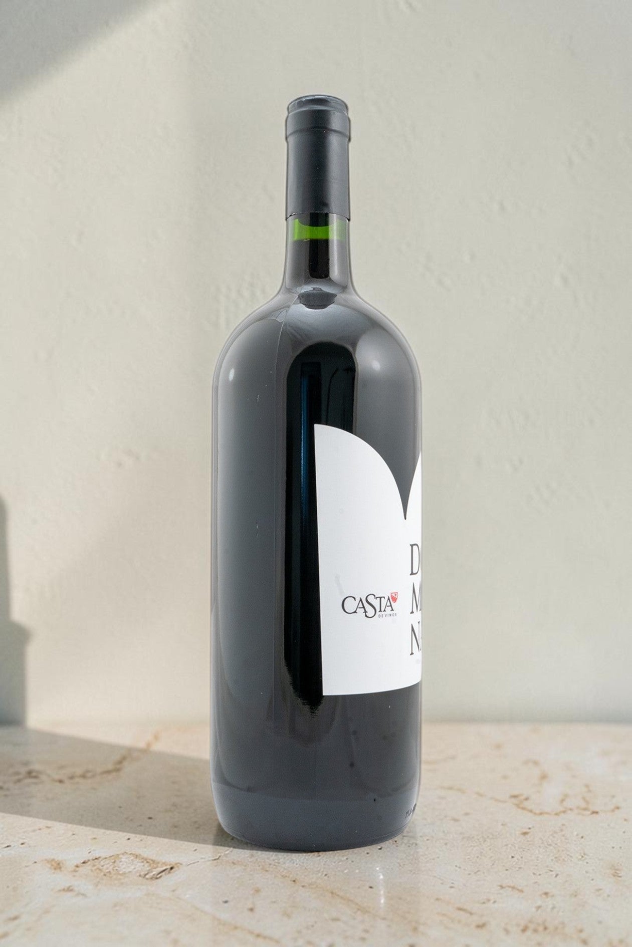 Botella de vino tinto Domina de Wellnex con etiqueta blanca sobre superficie clara