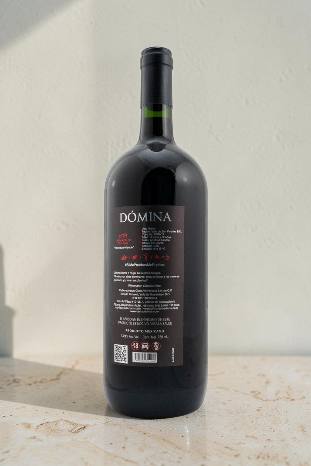 Botella de vino tinto Domina de Wellnex con etiqueta informativa sobre fondo blanco y luz natural