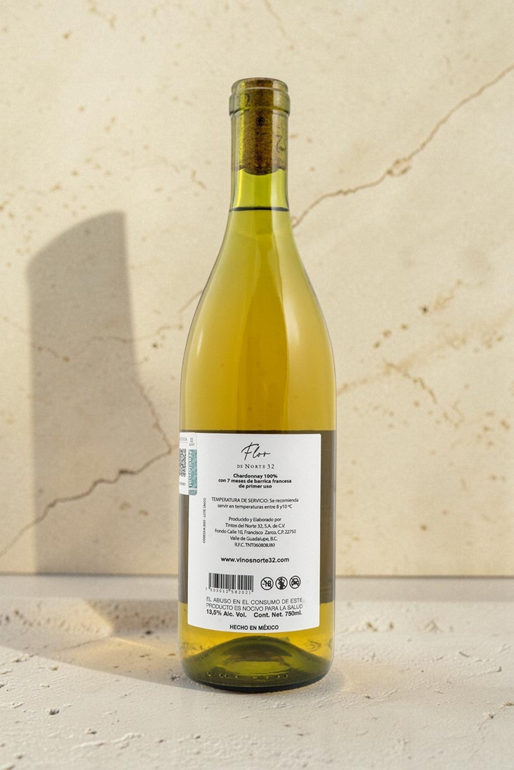Botella de vino blanco Wellnex Flor de Norte 32 Chardonnay con etiqueta detallada sobre superficie de piedra