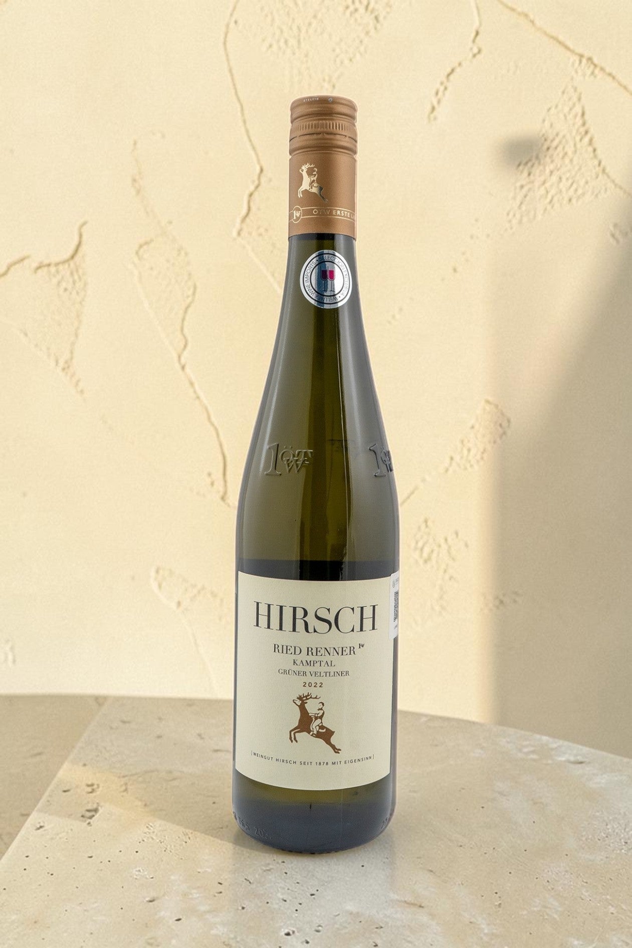 Botella de vino blanco Hirsch VB Ried Renner Kampler Gruner Veltliner de Wellnex sobre una mesa de piedra clara