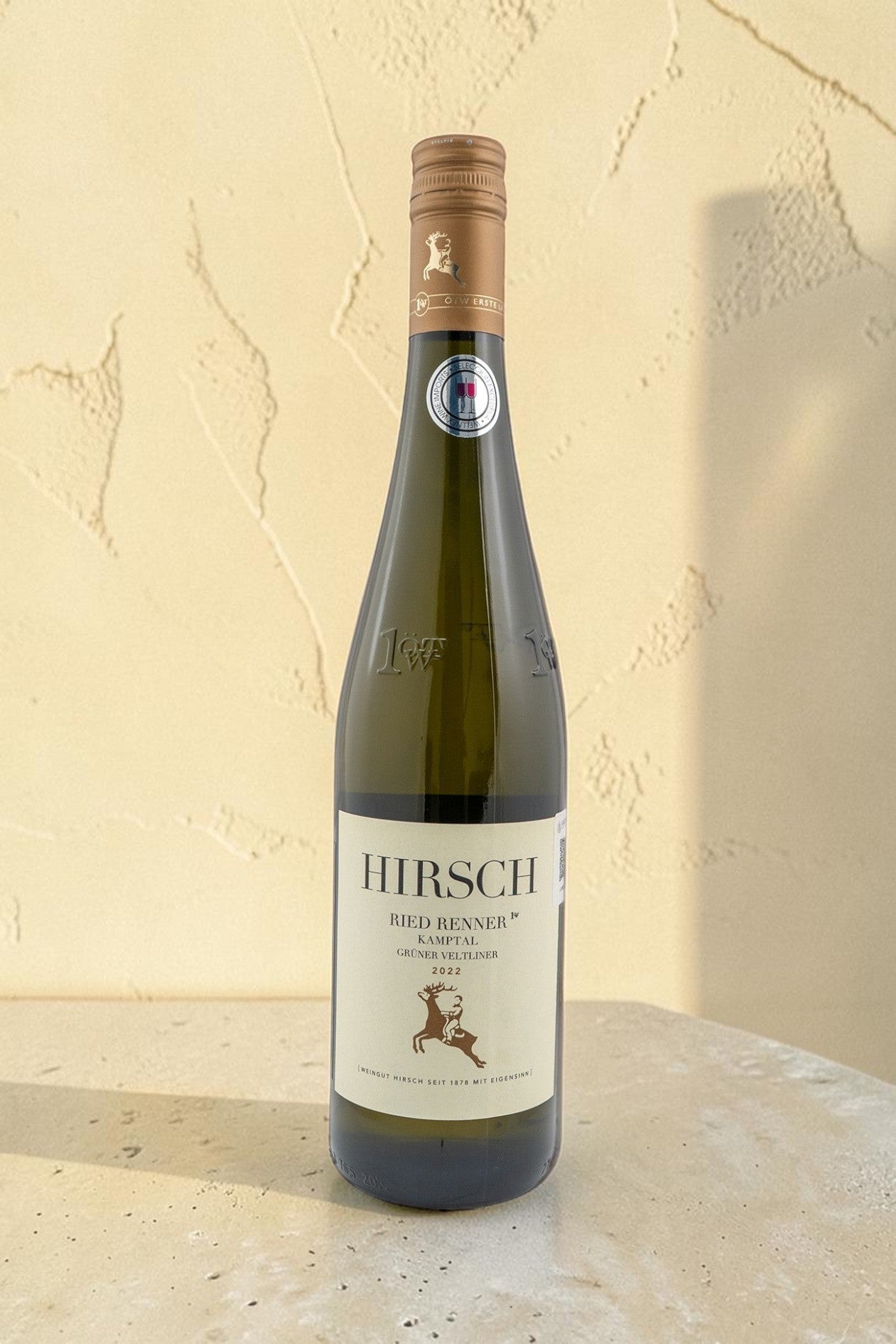 Botella de vino blanco Hirsch VB Ried Renner Kampler Gruner Veltliner 2022 de Wellnex sobre superficie clara