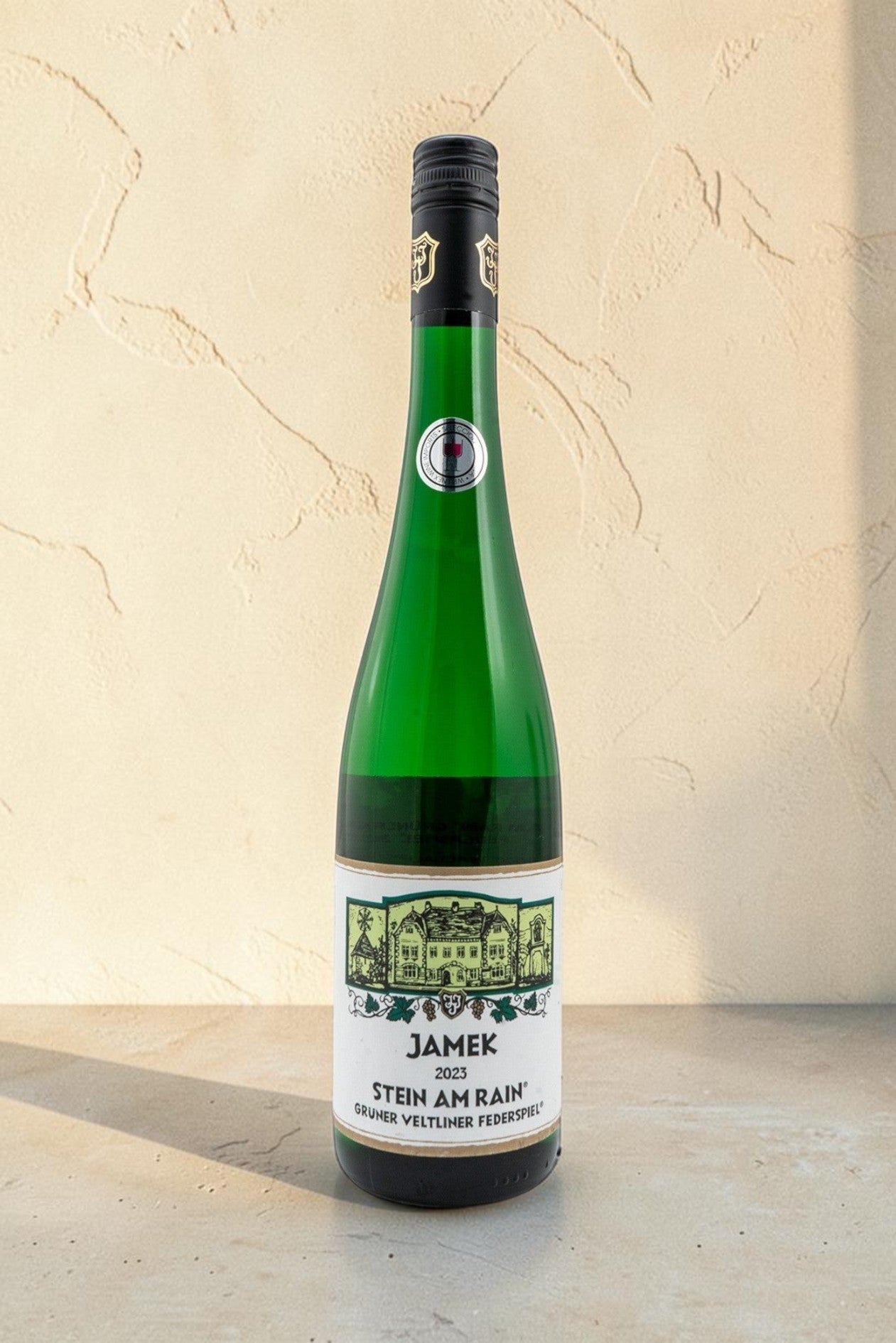 Botella de vino blanco Wellnex Jamek Stein AM Rain Gruner Veltliner Federspiel sobre superficie de piedra clara