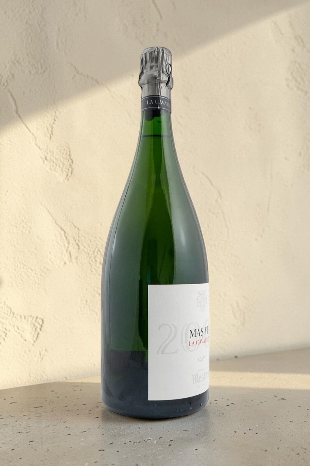 Botella Magnum de cava Mestres Cavateca 2000 Mas Via de Wellnex sobre superficie de piedra con luz natural