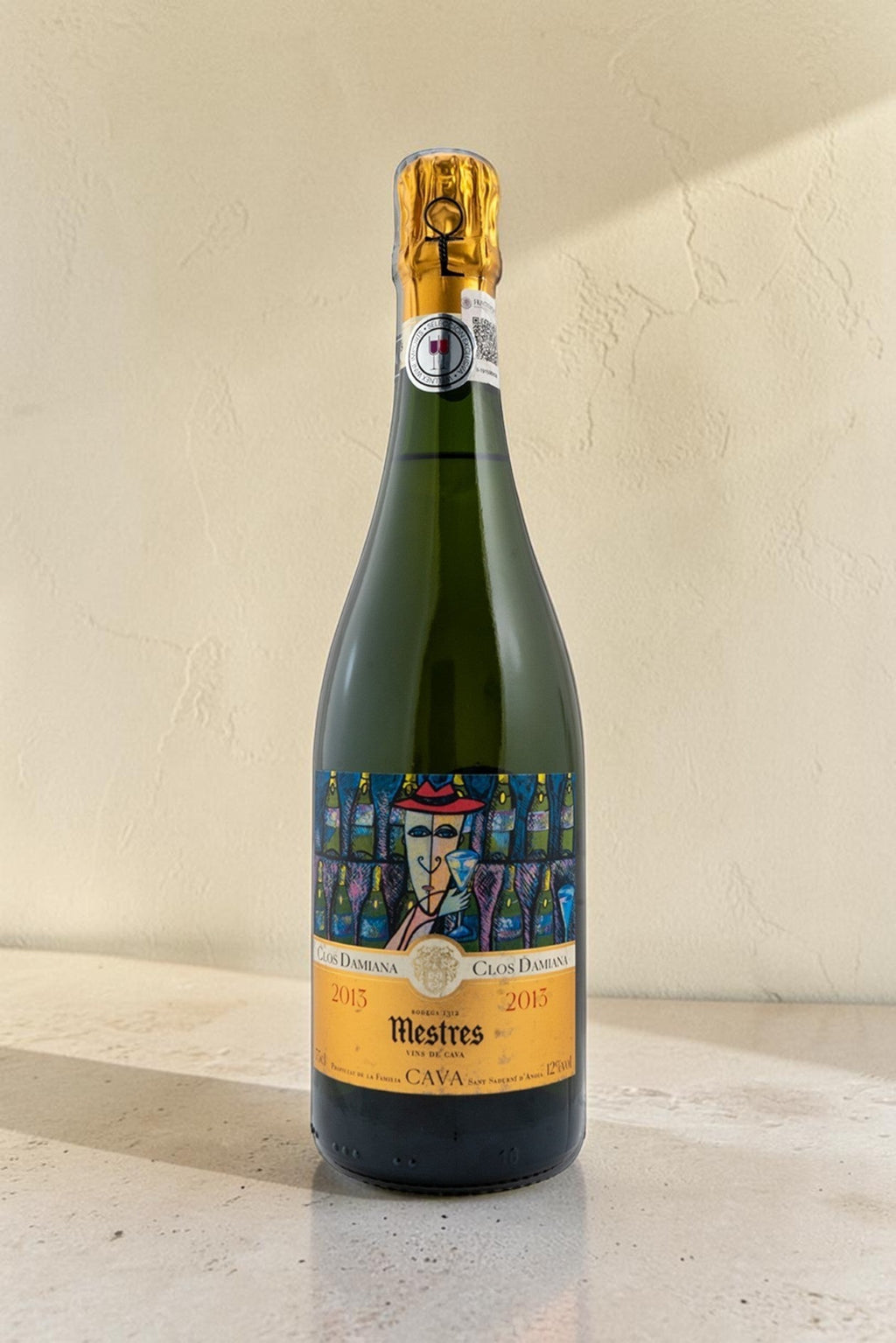 Botella de cava Wellnex Mestres Clos Damiana 2015 con etiqueta artística sobre superficie clara