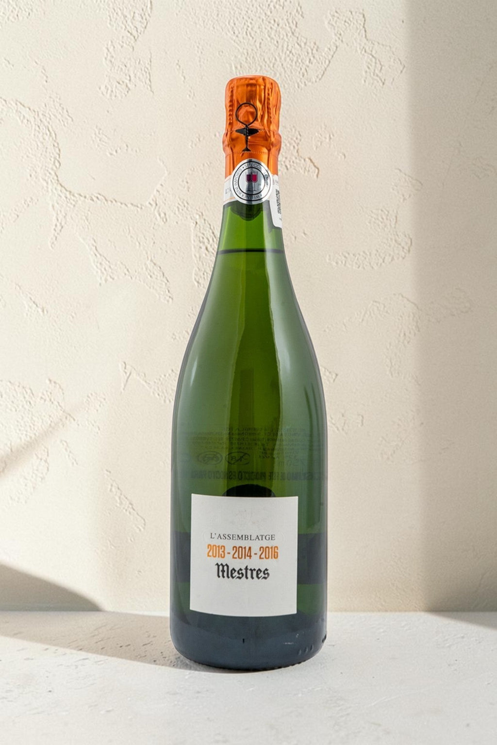 Botella de cava Wellnex Mestres Lassemblatge 13-14-16 con etiqueta elegante sobre fondo neutro