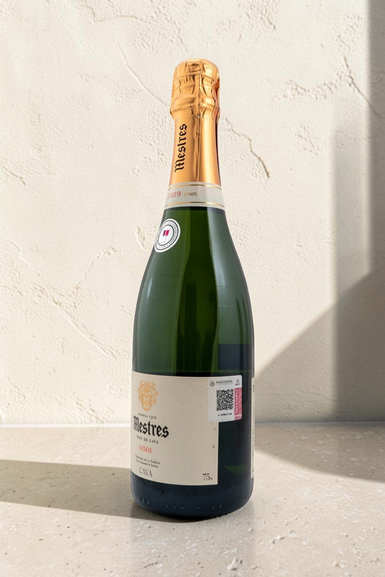 Botella de cava Wellnex Mestres Visol con etiqueta clásica y cápsula dorada sobre fondo neutro