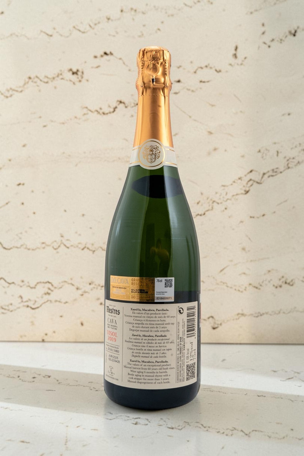 Botella de cava Wellnex Mestres Visol Gran Reserva con etiqueta detallada sobre superficie de piedra clara