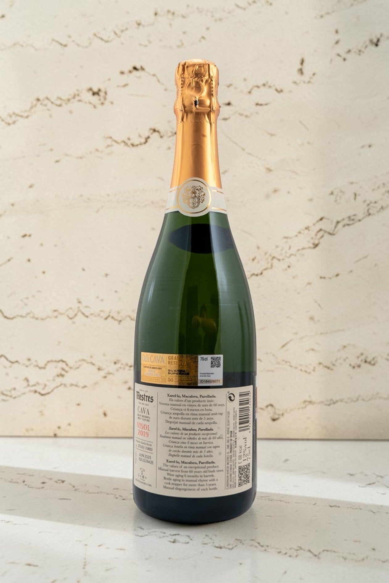 Botella de cava Wellnex Mestres Visol Gran Reserva con etiqueta detallada sobre superficie de piedra clara