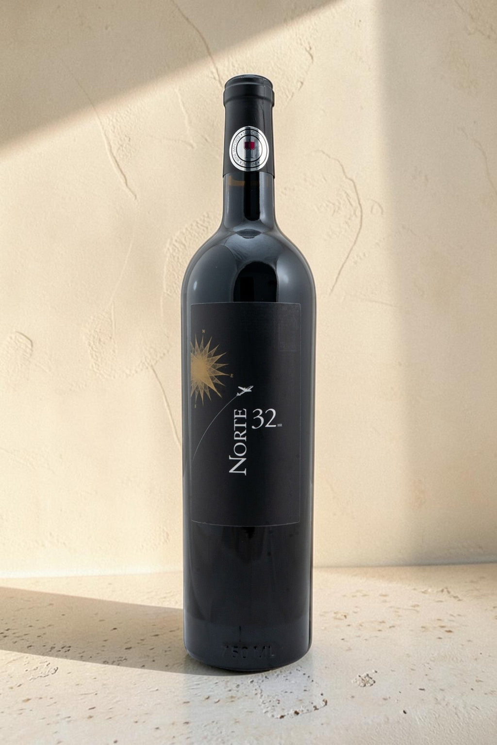 Botella de vino tinto Wellnex Norte 32 Etiqueta Negra con etiqueta elegante sobre fondo de piedra neutro