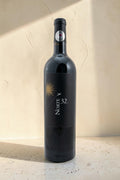 Botella de vino tinto Wellnex Norte 32 Etiqueta Negra con etiqueta elegante sobre fondo de piedra neutro