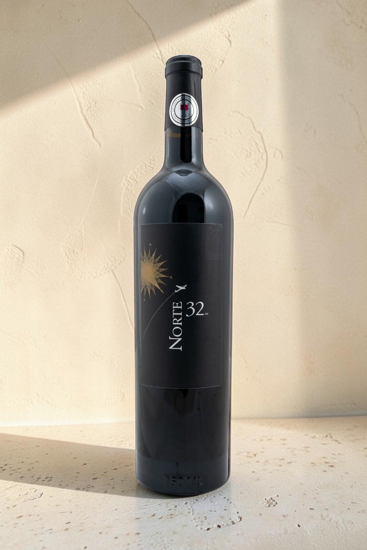 Botella de vino tinto Wellnex Norte 32 Etiqueta Negra con etiqueta elegante sobre fondo de piedra neutro