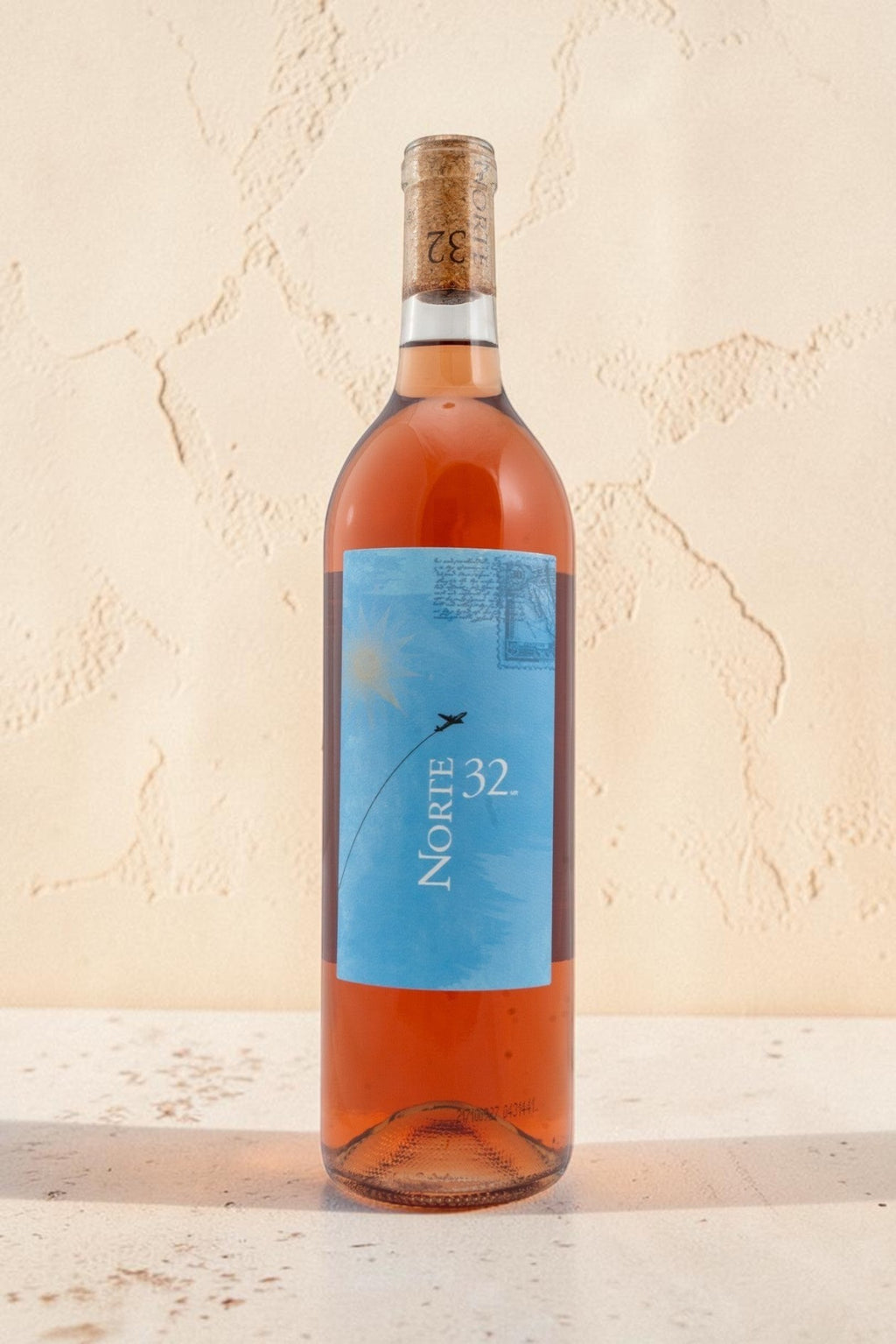 Botella de vino rosado Wellnex Norte 32 Etiqueta Azul con tonos asalmonados y etiqueta ilustrada sobre fondo claro