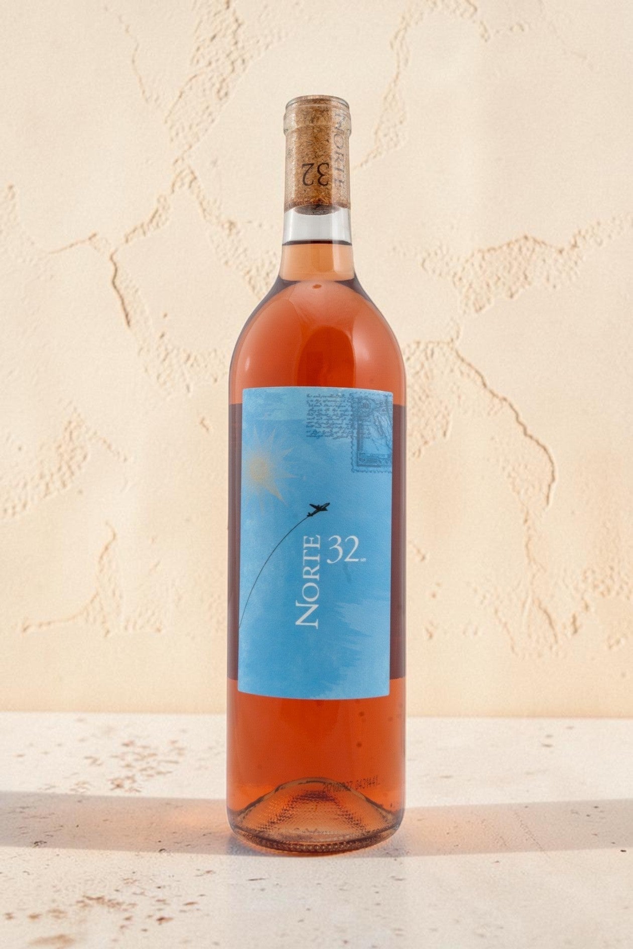 Botella de vino rosado Wellnex Norte 32 Etiqueta Azul con tonos asalmonados y etiqueta ilustrada sobre fondo claro