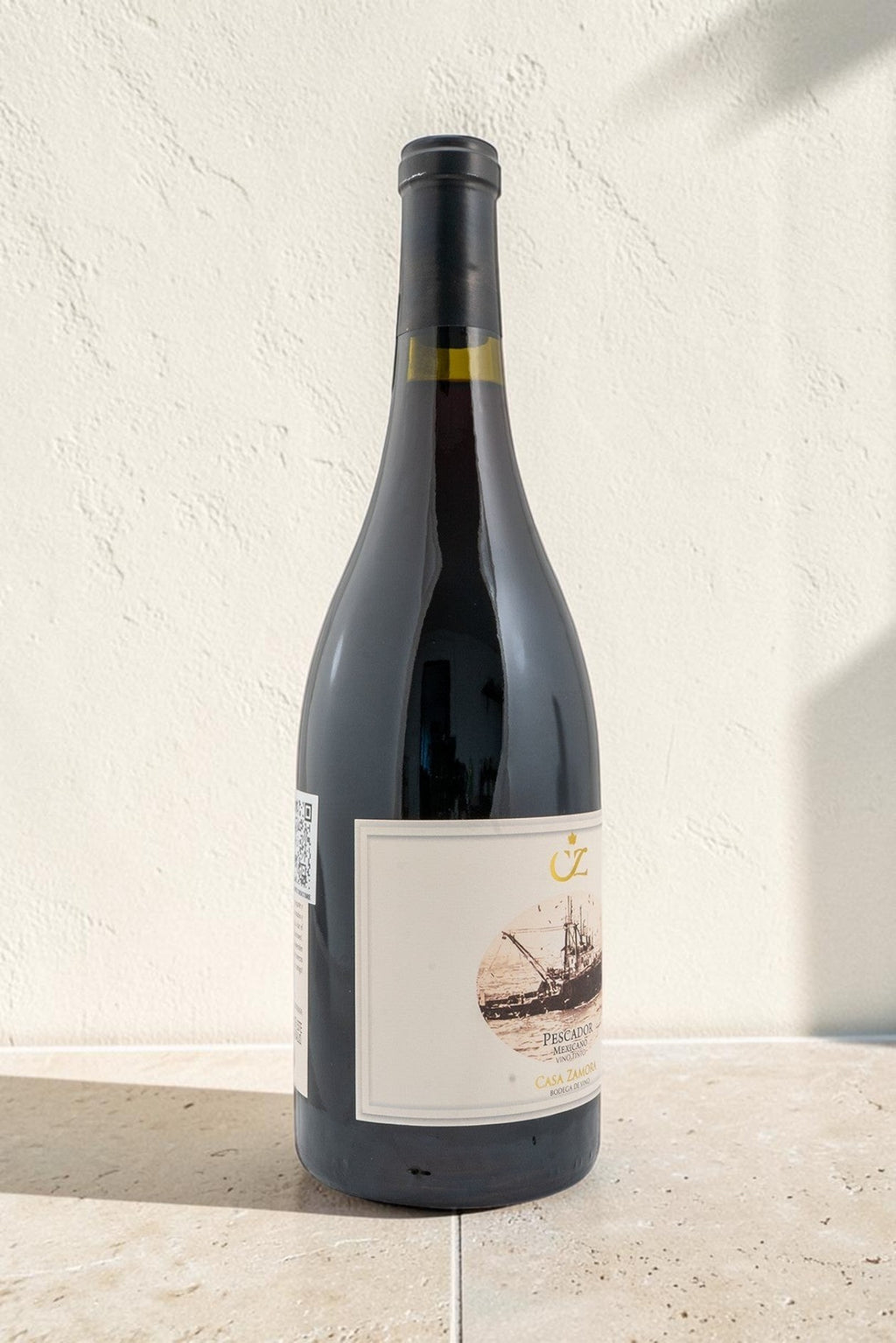 Botella de vino tinto Wellnex Pescador con etiqueta ilustrada de barco sobre fondo de piedra neutro