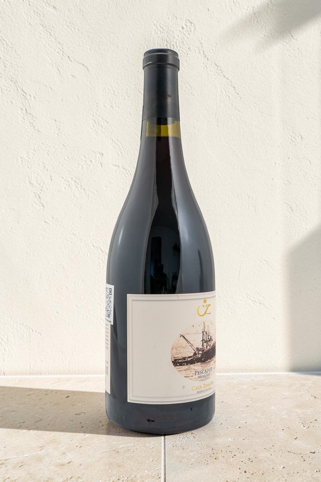 Botella de vino tinto Wellnex Pescador con etiqueta ilustrada de barco sobre fondo de piedra neutro