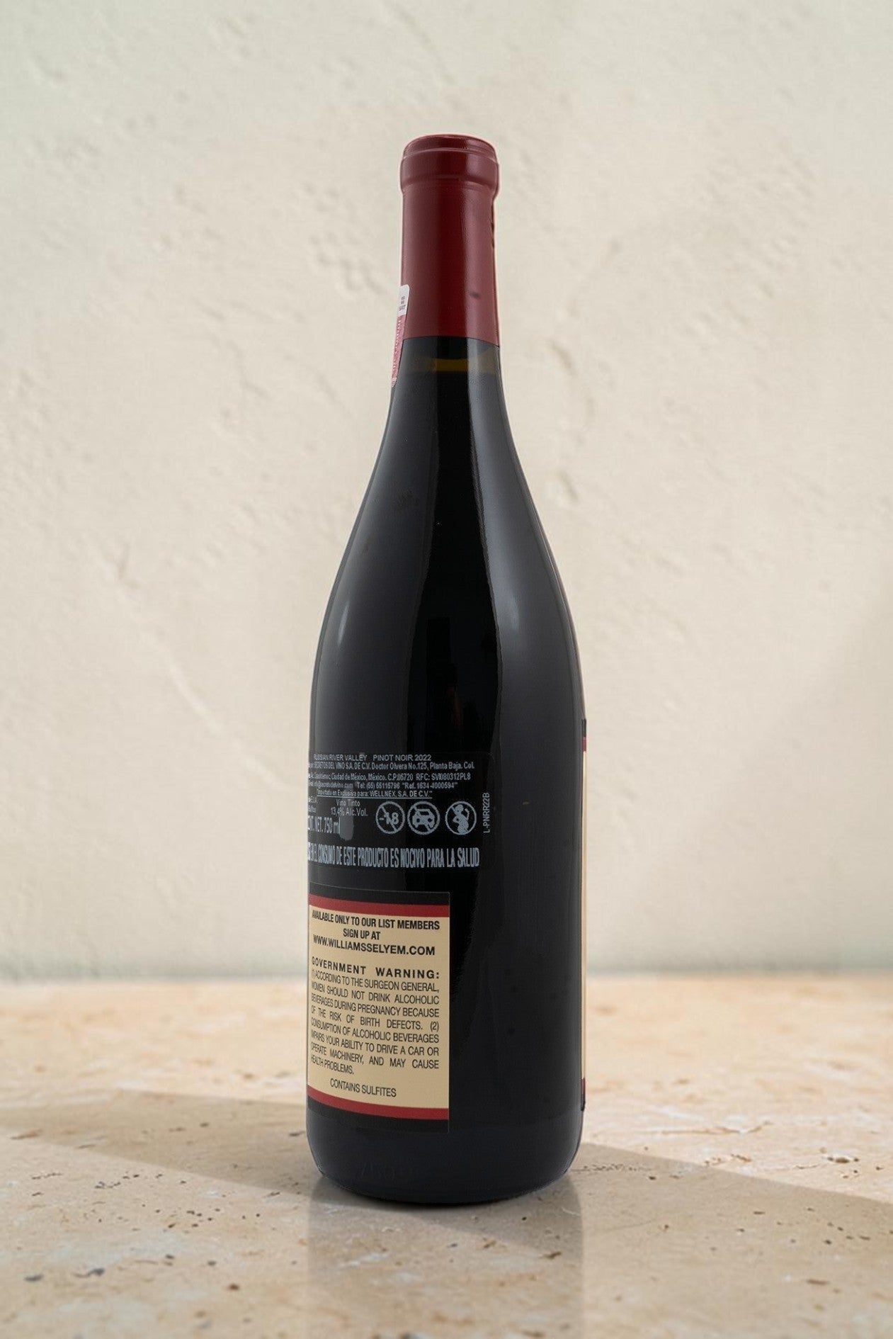 Botella de vino Pinot Noir Wellnex Russian River Valley con etiqueta informativa y cápsula roja sobre superficie clara