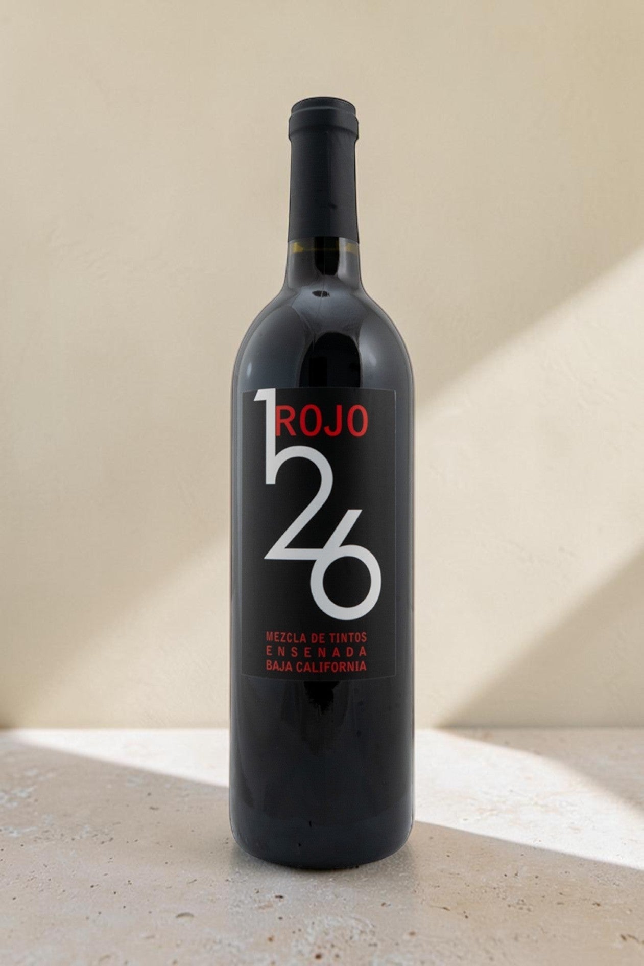 Botella de vino tinto Wellnex Rojo 126 con etiqueta negra moderna y tipografía blanca sobre fondo neutro