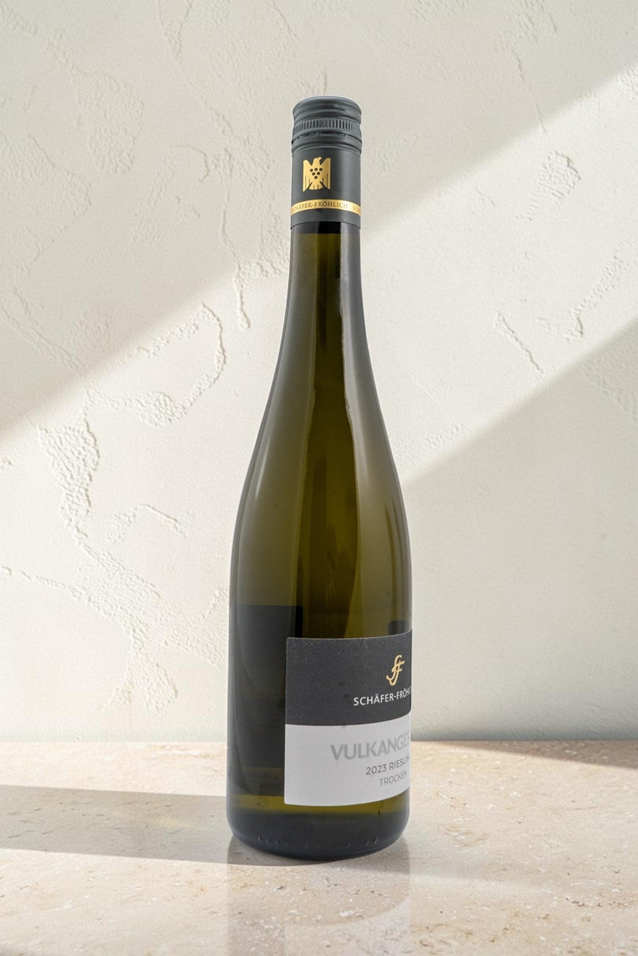 Botella de vino blanco Wellnex Schafer Frohlich Vulkangestein Riesling Trocken con etiqueta elegante sobre fondo claro