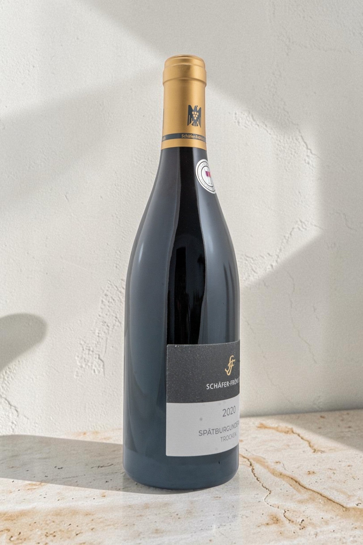 Botella de vino tinto Wellnex Schafer Frohlich Spatburgunder 2020 con etiqueta elegante sobre superficie de piedra