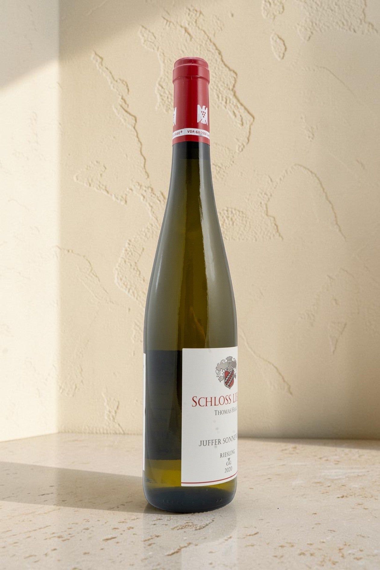 Botella de vino blanco Wellnex Schloss Lieser Juffer Sonnenuhr Riesling GG sobre superficie de piedra clara