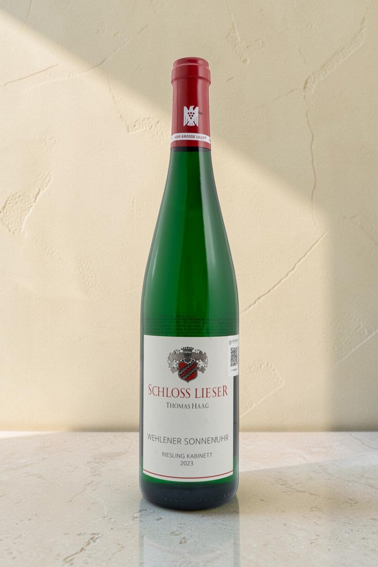 Botella de vino blanco Riesling Kabinett Schloss Lieser Wehlener Sonnenuhr de Wellnex sobre superficie clara