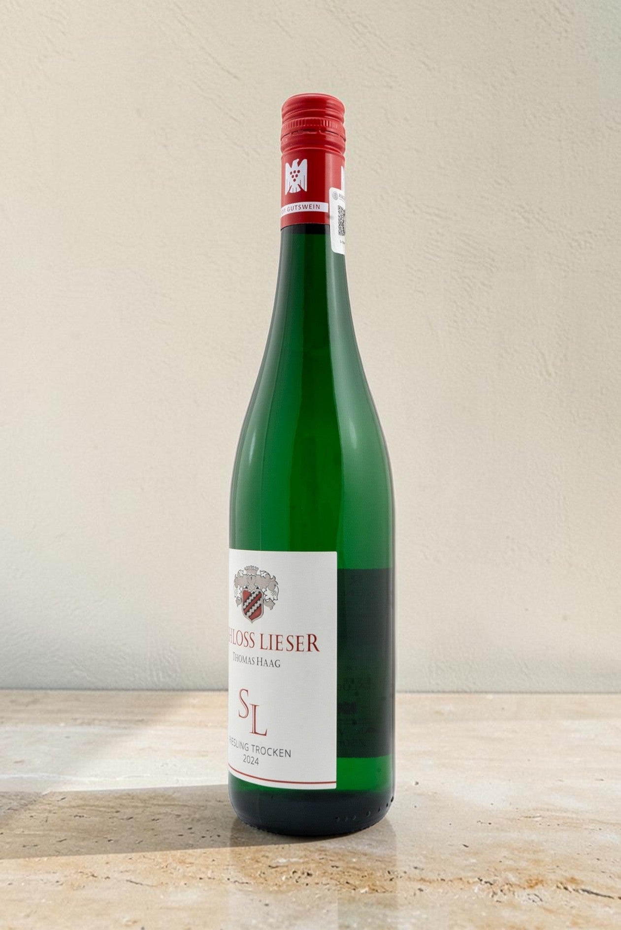 Botella de vino blanco Wellnex Schloss Lieser Riesling Trocken con etiqueta elegante y cápsula roja sobre fondo claro