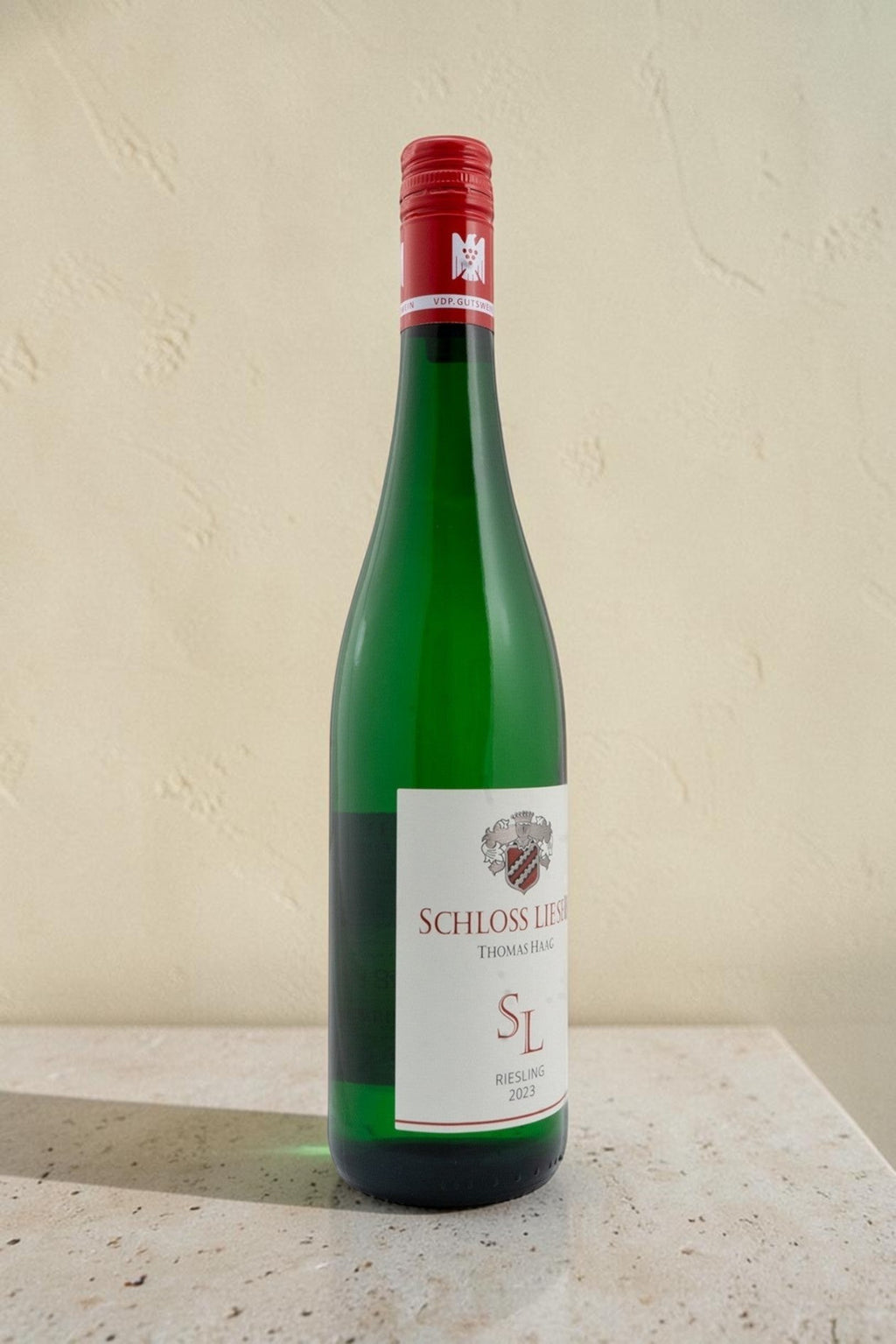 Botella de vino blanco Wellnex Schloss Lieser Riesling 2023 con tapón de rosca rojo sobre fondo neutro