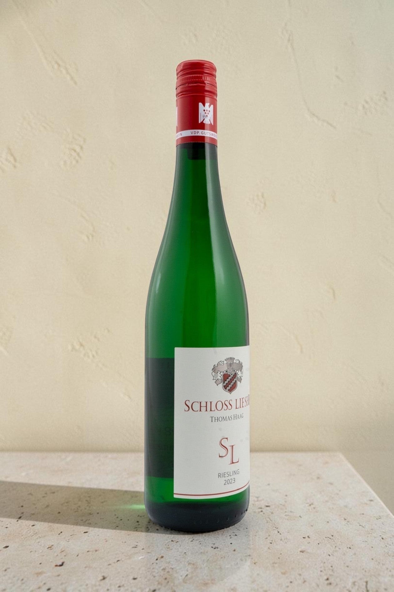 Botella de vino blanco Wellnex Schloss Lieser Riesling 2023 con tapón de rosca rojo sobre fondo neutro