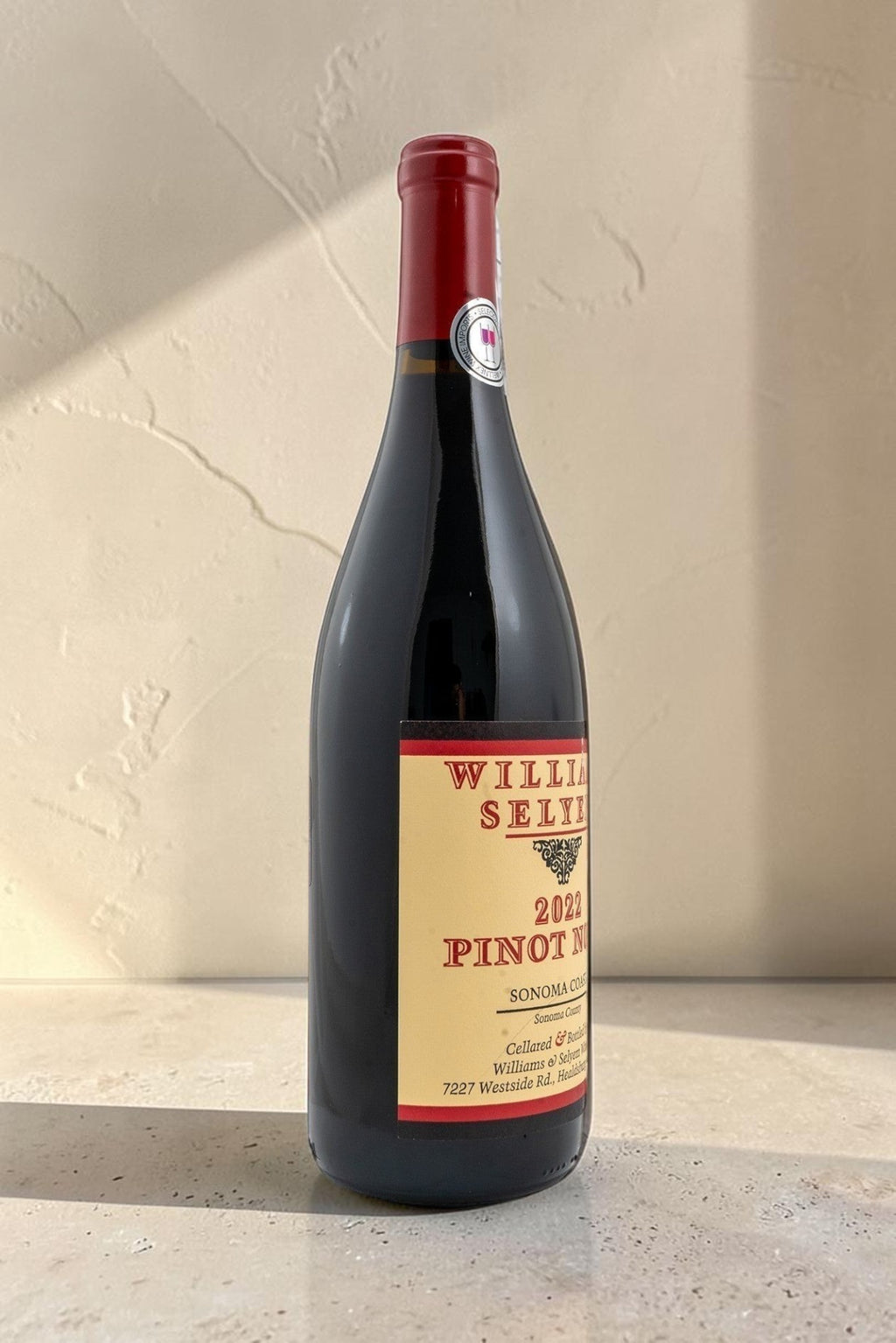 Botella de vino tinto Wellnex Sonoma Coast Pinot Noir 2022 con etiqueta clásica sobre fondo de piedra iluminado
