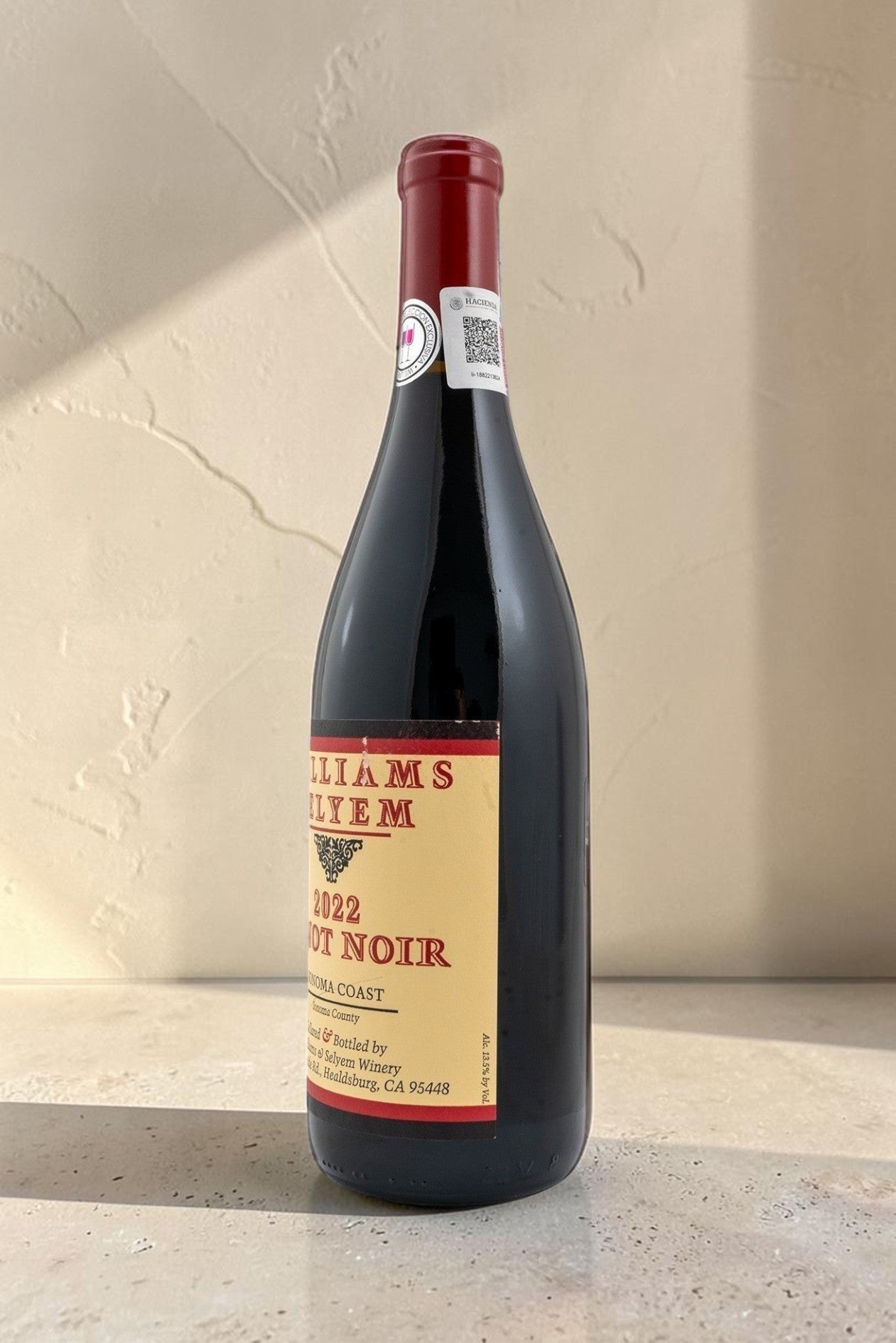 Botella de vino tinto Wellnex Sonoma Coast Pinot Noir 2022 con etiqueta clásica sobre fondo de piedra y hojas