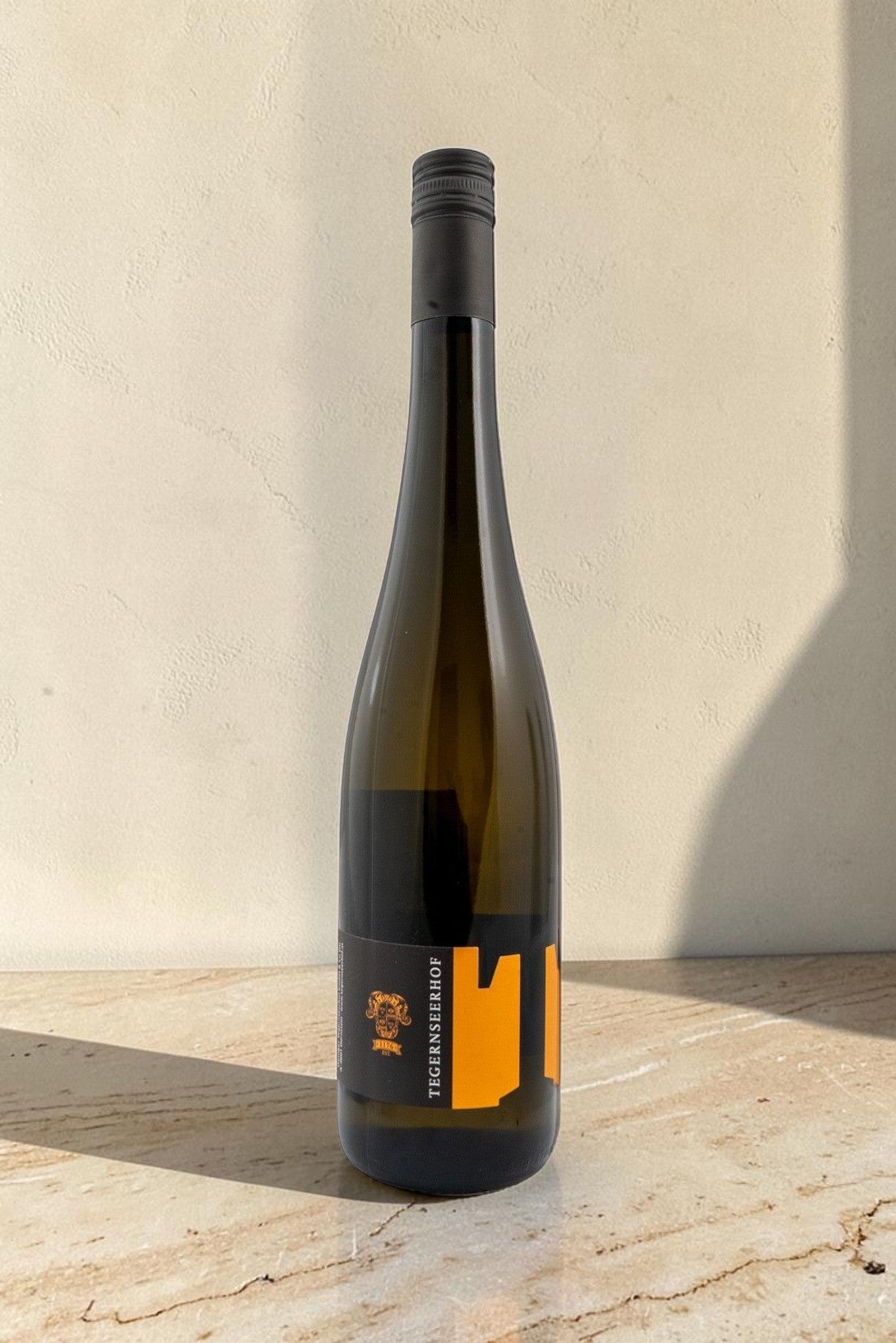 Botella de vino blanco Wellnex Tegernseerhof Gruner Veltliner Federspiel con etiqueta negra y naranja