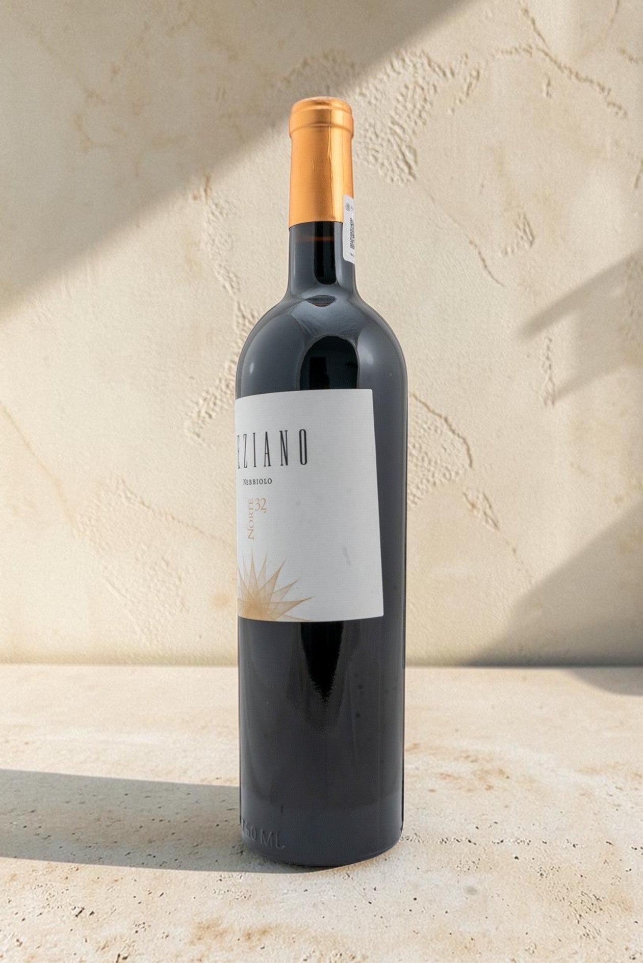 Botella de vino tinto Wellnex Teziano Nebiolo con etiqueta elegante sobre fondo de piedra clara